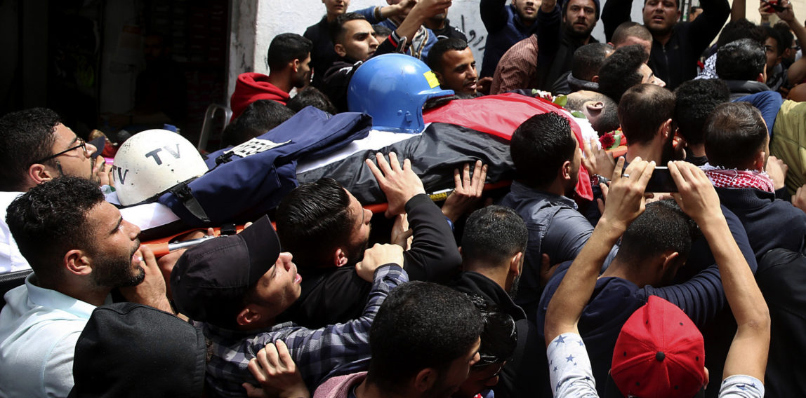 Mourners carry the body of Palestinian journalist Ahmed Abu Hussein, who was killed by Israeli troops while covering a border protest, during his funeral in the Jebaliya refugee camp, Gaza Strip, April 26, 2018. (AP/Adel Hana)