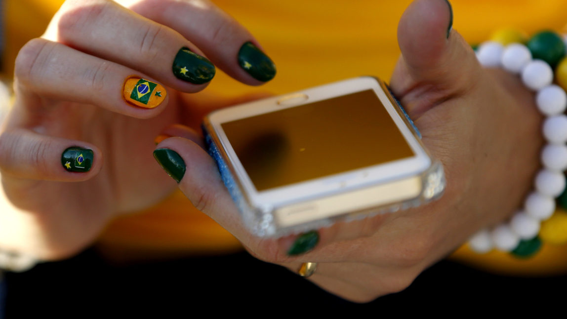 Lena Helom, of Sao Paulo, Brazil, holds a cell phone before the start of the World Cup opening match between Brazil and Croatia at Itaquerao Stadium in Sao Paulo, Brazil, June 12, 2014. (AP/Julio Cortez)