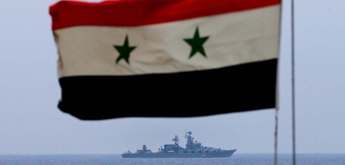 Russian navy missile cruiser Moskva on patrol in the Mediterranean Sea near the Syrian coast, with a Syrian flag in front, Dec. 17, 2015 (Vadim Savitsky/Russian Defense Ministry)