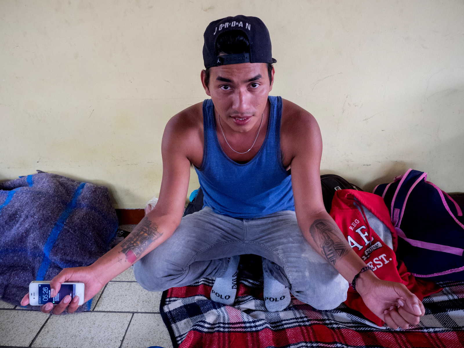Inside the Casa del Peregrino, Israel Greñaldo, a migrant from Guatemala, shows off his tattoos, on his left arm he has an image of La Bestia, the freight train many migrants ride through Mexico as part of their journey to the United States, and on his right arm a tattoo depicting Antigua, Guatemala, April 10, 2018.