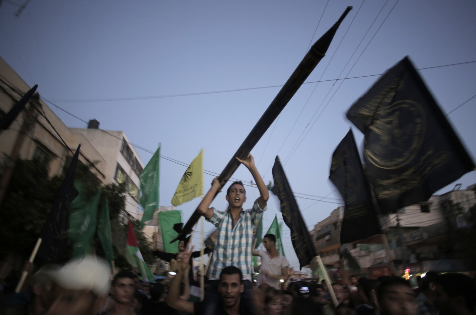 2014年8月26日，巴勒斯坦人在加沙城庆祝2014年停火，一名男子手持一枚模拟卡萨姆火箭。Khalil Hamra |美联社