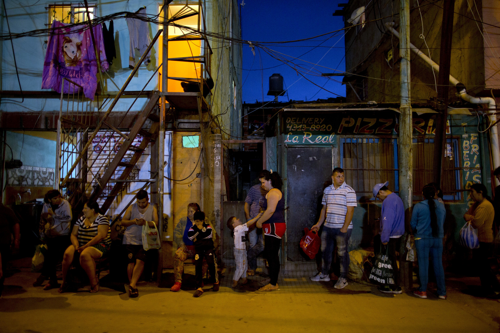 People line up outside Norma Colque's home to fill their containers with free food. Colque, who gets food from the state to serve about 200 a day, says she has had to stretch the pasta and stew because twice as many people are lining up for food. Natacha Pisarenko | AP