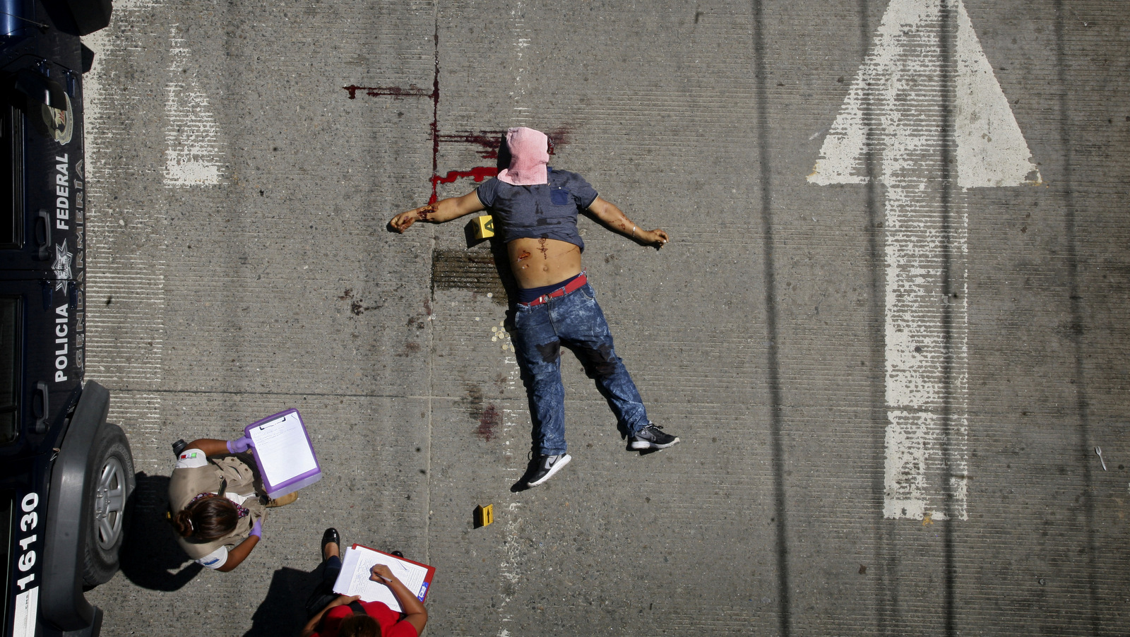 Police investigators take notes by the body of a man shot in broad daylight in Acapulco, Mexico, Aug. 13, 2017. (AP/Bernandino Hernandez)