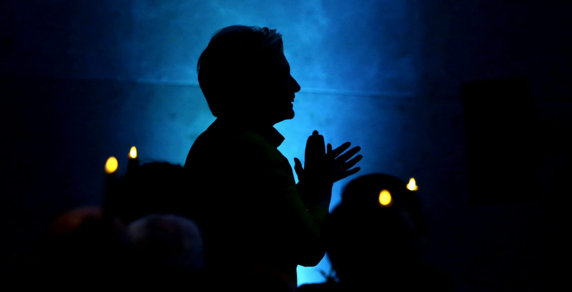 Former Secretary of State Hillary Clinton appears in silhouette as she applauds before taking the stage to speak during a fundraising event for Big Sister Association of Greater Boston, Dec. 5, 2017, in Boston. Clinton was presented with the organization's Believe in Girls award during the event. (AP/Steven Senne)