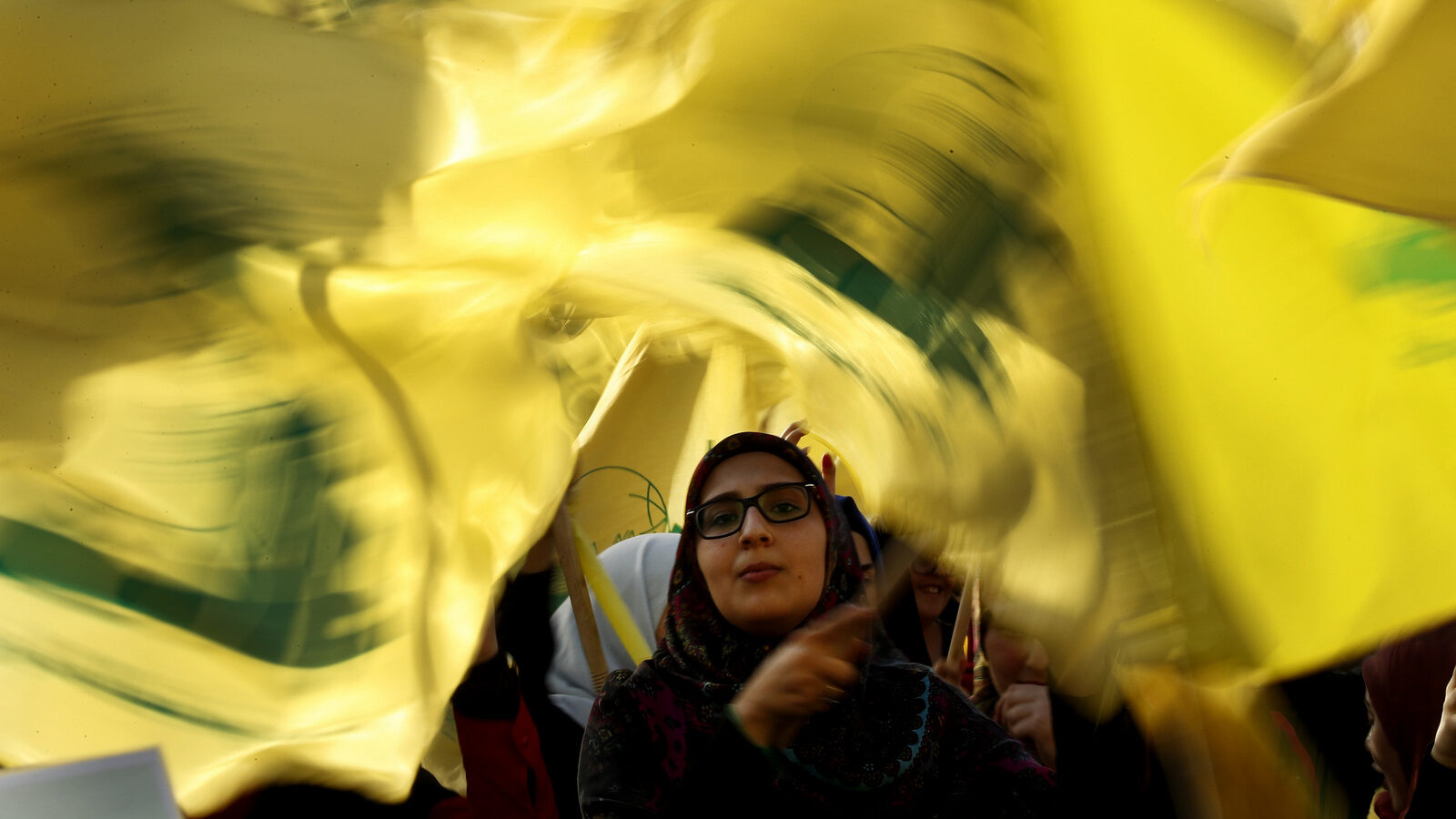 A Hezbollah supporter waves her group flags during an election campaign speech by Hezbollah leader Sayyed Hassan Nasrallah, in a southern suburb of Beirut, Lebanon, April 13, 2018. (AP/Hussein Malla)