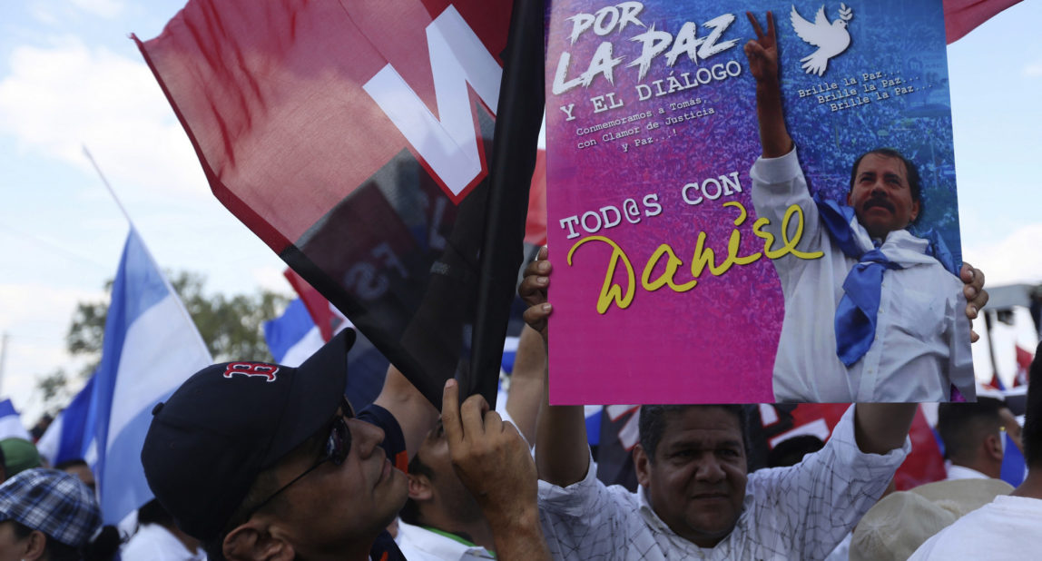 Supporters of Nicaragua's President Daniel Ortega hold up his photo and Sandinista National Liberation Front (FSLN) flags during a government event at Las Victorias square in Managua, Nicaragua, April 30, 2018. (AP/Alfredo Zuniga)