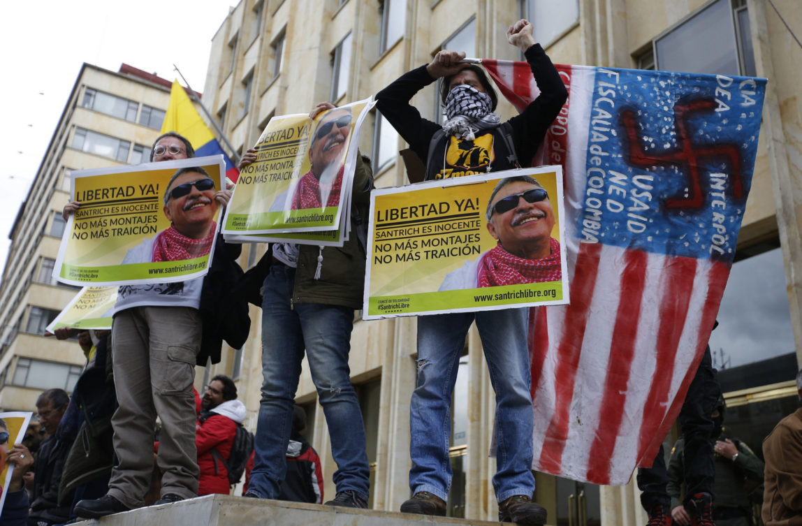 Supporters of Seuxis Paucias Hernandez-Solarte, better known by his alias Jesus Santrich, a leader of the former Revolutionary Armed Forces of Colombia (FARC), hold posters asking for his freedom during a demonstration marking May Day to honor workers, in Bogota, Colombia, May, 1, 2018. (AP/Fernando Vergara)