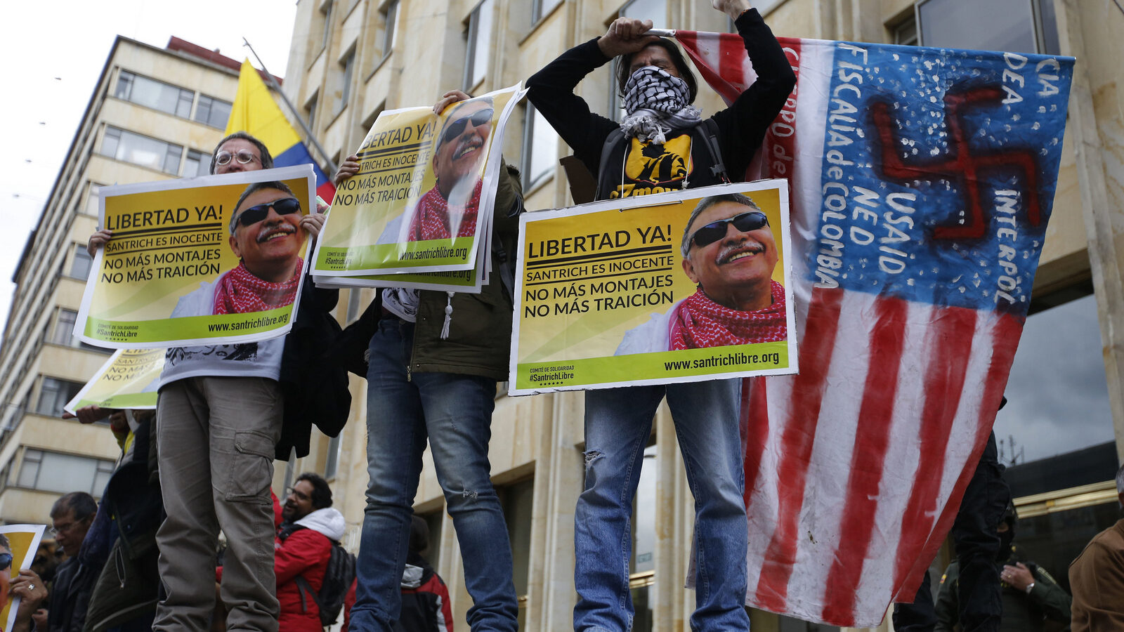Supporters of Seuxis Paucias Hernandez-Solarte, better known by his alias Jesus Santrich, a leader of the former Revolutionary Armed Forces of Colombia (FARC), hold posters asking for his freedom during a demonstration marking May Day to honor workers, in Bogota, Colombia, May, 1, 2018. (AP/Fernando Vergara)
