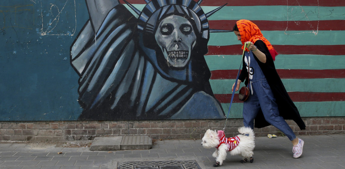 A woman walks her dog past a mural depicting a nefarious Statue of Liberty on the wall of the former U.S. Embassy in Tehran, Iran, May. 8, 2018. Vahid Salemi | AP