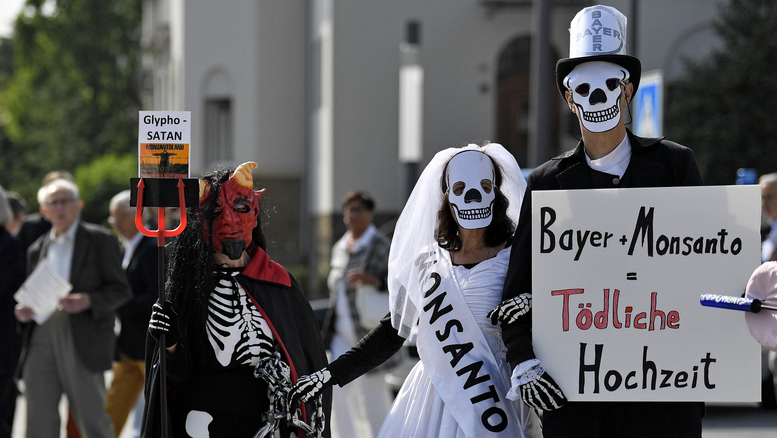 Activists protest against the acquisition of the US agrochemical company Monsanto by the German Bayer company outside the annual shareholders meeting of Bayer in Bonn, Germany, Friday, May 25, 2018. (AP Photo/Martin Meissner)