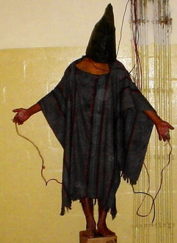 An unidentified detainee standing on a box with a bag on his head and wires attached to him in late 2003 at the Abu Ghraib prison in Baghdad, Iraq.