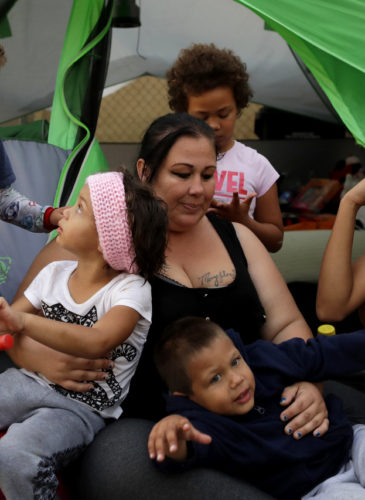 Christine Wade sits among her children in front of their donated tent in the city-sanctioned encampment on a parking lot in San Diego. They are, from left, Shawnni, 12, Roland, 4, Rayahna, 3, Jaymason, 2, Brooklyn, 8, and Shaccoya, 14. The Wade family is among several hundred people living in the city's first campground open for the homeless, set up to curb the worst Hepatitis A outbreak in the United States in decades. Gregory Bull | AP