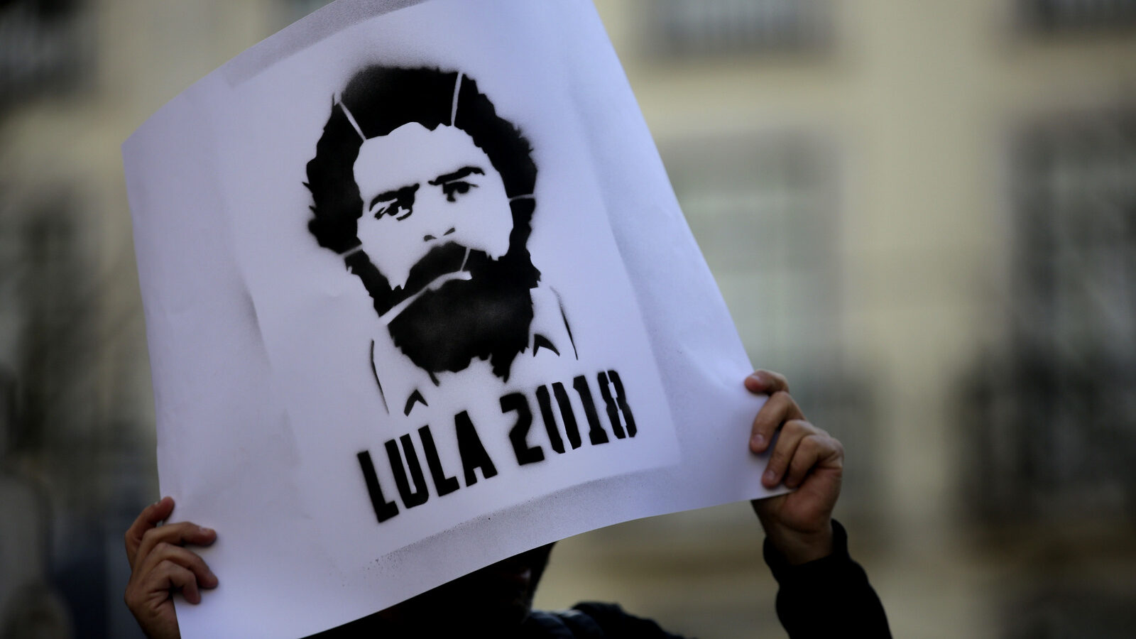 A protestor holds up a poster with a picture of Brazil's former President Luiz Inacio Lula da Silva during a demonstration in his support in Lisbon, Monday, April 9, 2018. Lula da Silva was taken into police custody Saturday, April 7, after the Brazilian Supreme Federal Tribunal ruled against his petition to remain free while he continued to appeal his 12-year sentence for money laundering and corruption. (AP Photo/Armando Franca)