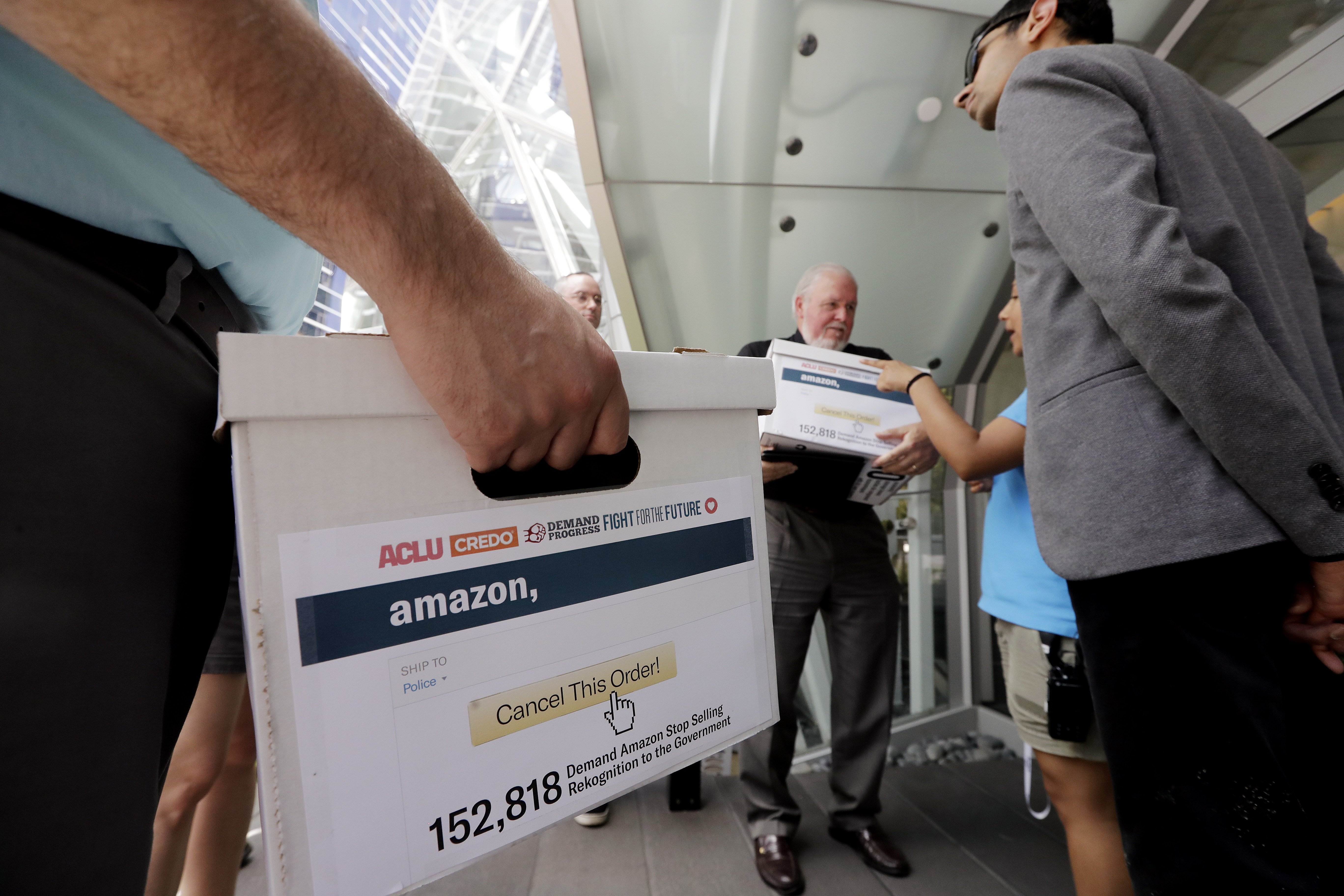 Rev. Paul Benz, center, and Shankar Narayan, legislative director of the ACLU of Washington, right, stand with others as they wait to deliver petitions at Amazon headquarters, June 18, 2018, in Seattle. Representatives of community-based organizations urged Amazon at a news conference to stop selling its face surveillance system, Rekognition, to the government. They later delivered the petitions to Amazon. Elaine Thompson | AP