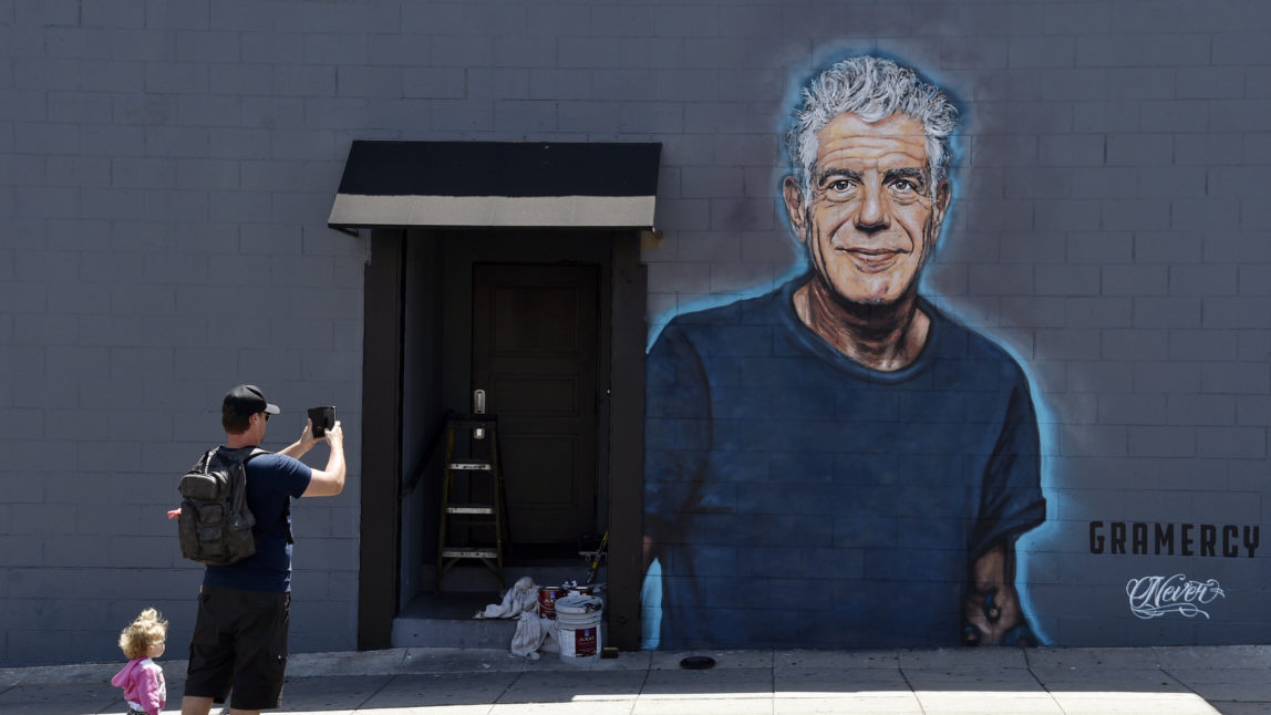 Food writer Hadley Tomicki, of Los Angeles, is accompanied by his daughter Kira, 1, as he takes a picture of a new mural of the late chef/writer/television personality Anthony Bourdain, created by artist Jonas Never, June 18, 2018, on a side wall of the new restaurant Gramercy in Santa Monica, Calif. Bourdain died Friday, June 8, in France in an apparent suicide. Chris Pizzello | Invision | AP)