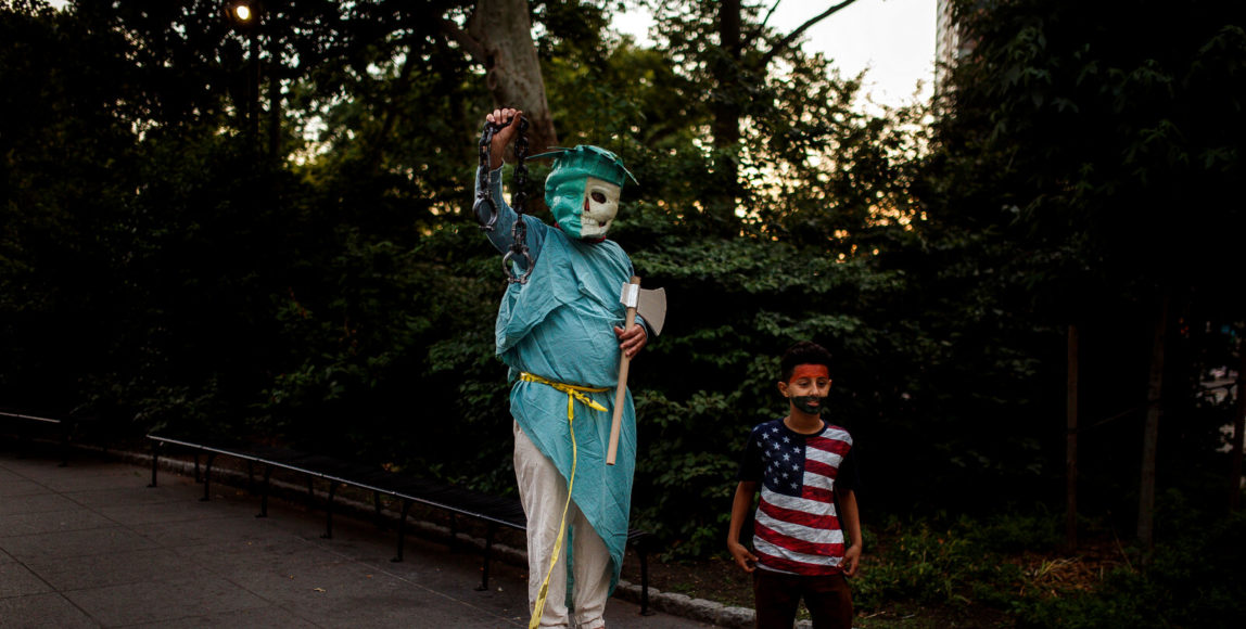 A child stands next to a protester representing the Statue of Liberty Trump's Muslim ban on June 26, 2018, in New York. Civil rights organizations, expressed outrage and disappointment at the U.S. Supreme Court's decision Tuesday to uphold President Donald Trump's ban. Andres Kudacki | AP