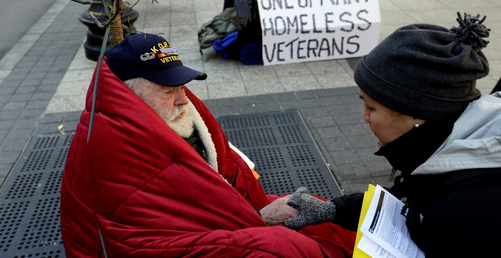 Homeless Korean War veteran Thomas Moore, 79, left, speaks with Boston Health Care for the Homeless street team outreach coordinator Romeena Lee on a sidewalk in Boston. Steven Senne | AP