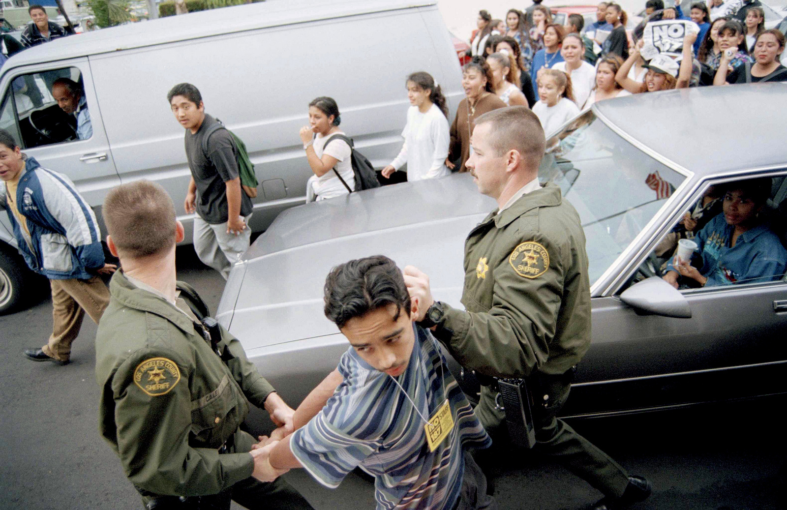 洛杉矶郡警长的代表在学生反对1994年11月2日提出的187号提案时举行了一个年轻的抗议者。美联社