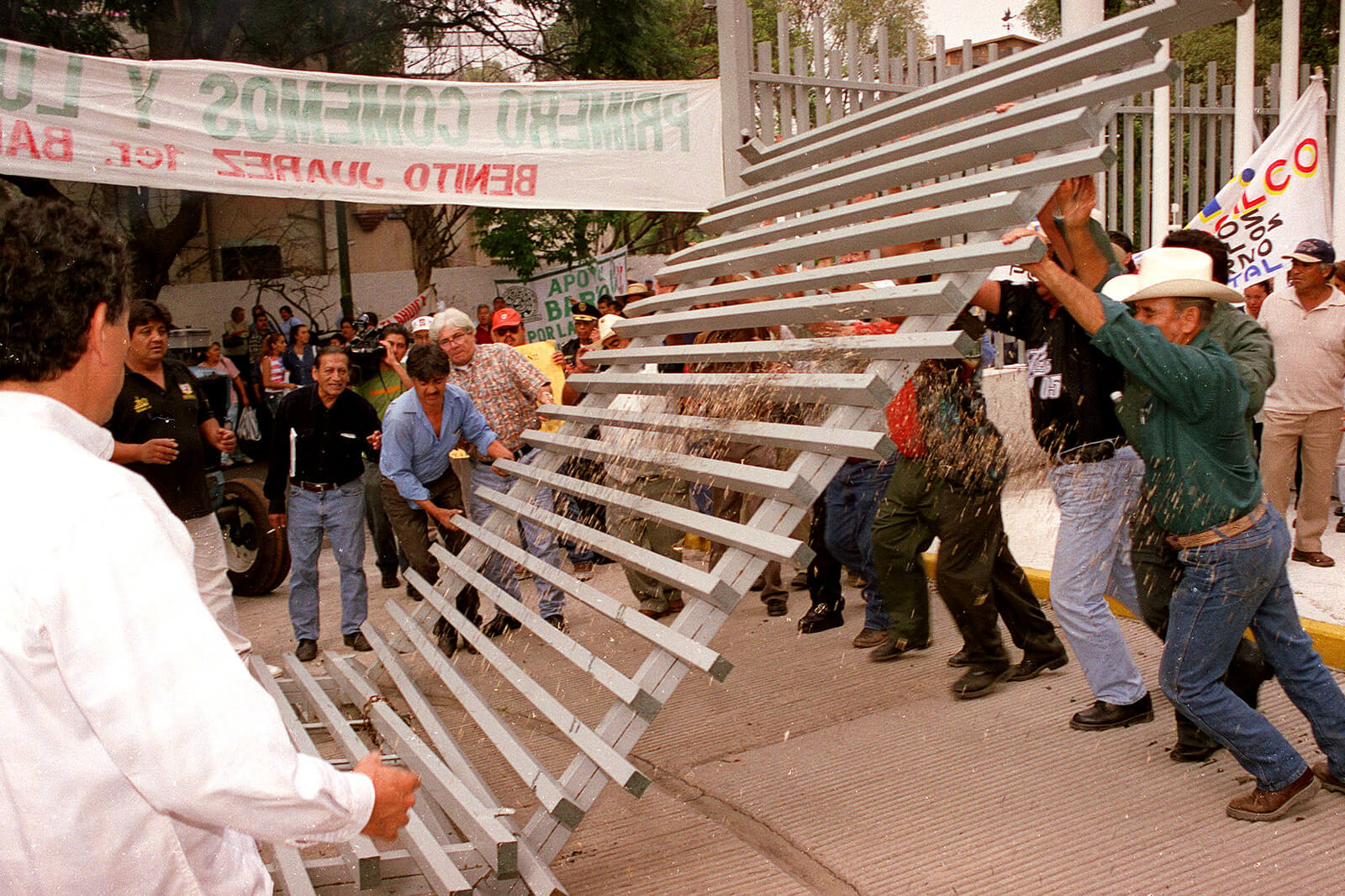 2002年10月29日，在墨西哥城举行的反对北美自由贸易协定的抗议活动中，农民打破了经济部的大门.Ismael Rojas |美联社