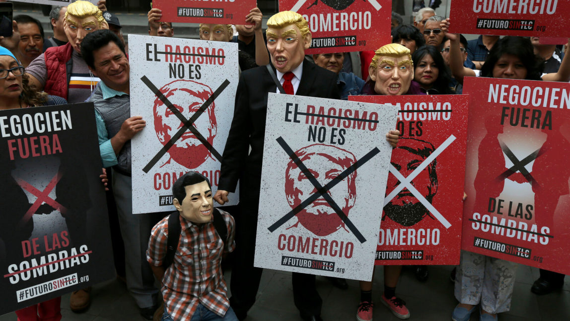 Mexican activists carry signs that read in Spanish "Racism is not commerce," at a protest against the seventh round of the North American Free Trade Agreement, NAFTA, renegotiations, in front of the foreign relations office in Mexico City, Feb. 27, 2018. Marco Ugarte | AP