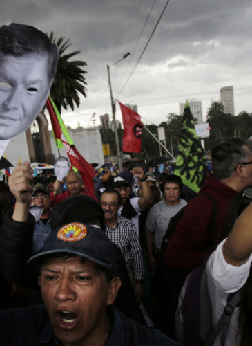Supporters of Ecuador's former President Rafael Correa hold up images of his face as they protest an attempt to prosecute him, outside the National Assembly in Quito, Ecuador, June 14, 2018. Dolores Ochoa | AP