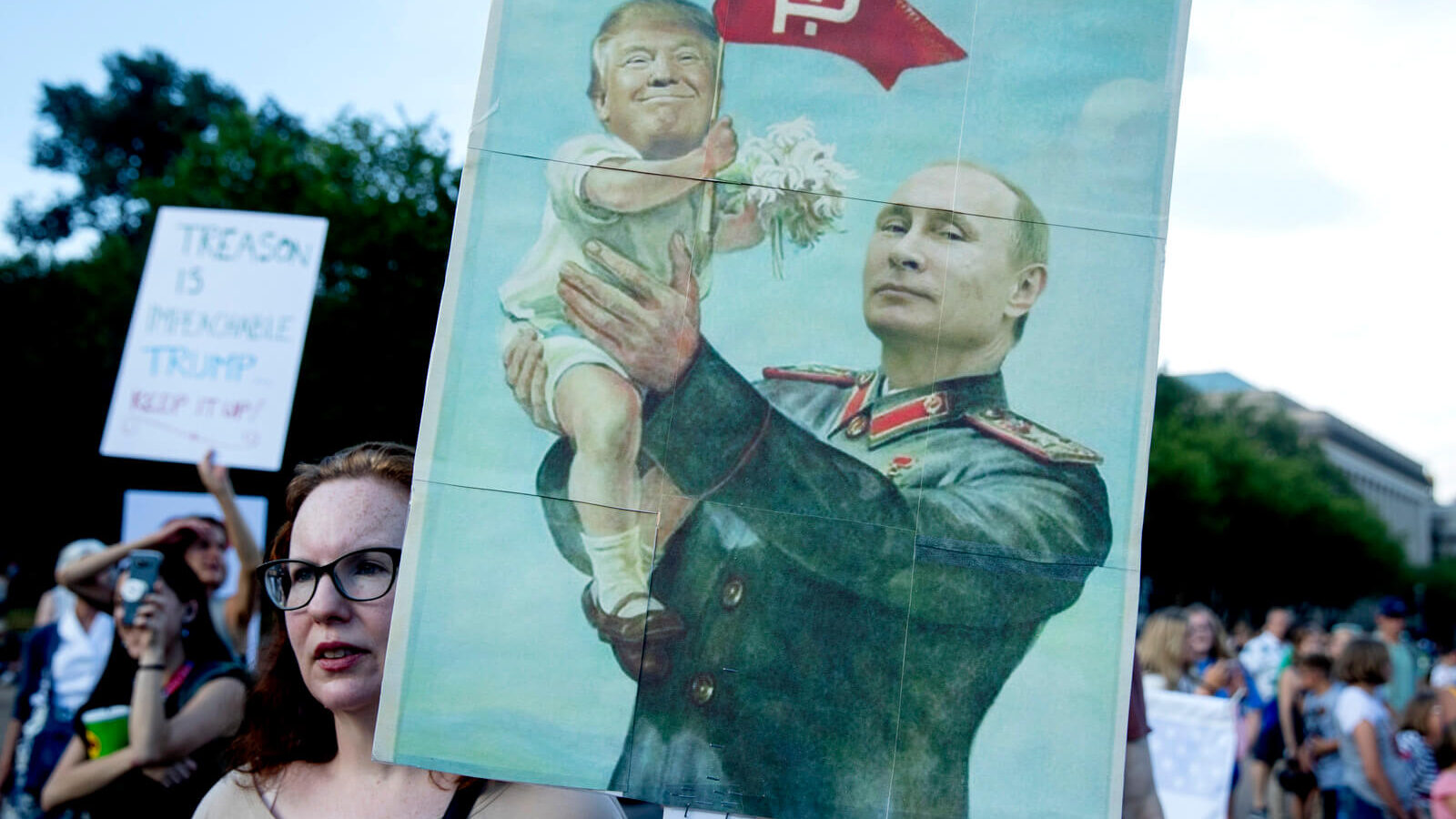 A woman holds a sign depicting Russian President Vladimir Putin and President Donald Trump during a protest outside the White House, July 17, 2018, in Washington. Andrew Harnik | AP
