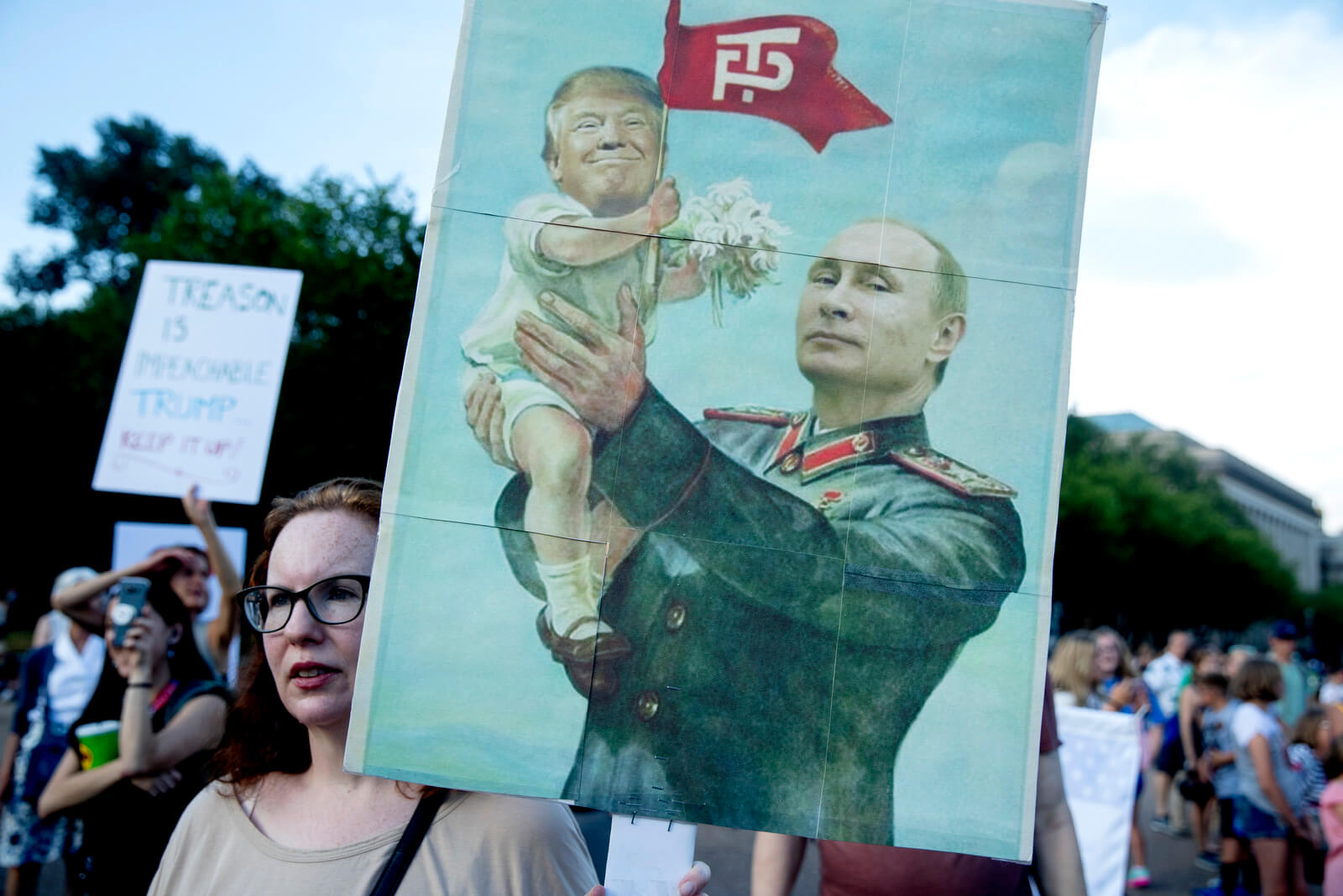 A woman holds a sign depicting Russian President Vladimir Putin and President Donald Trump during a protest outside the White House, July 17, 2018, in Washington. Andrew Harnik | AP