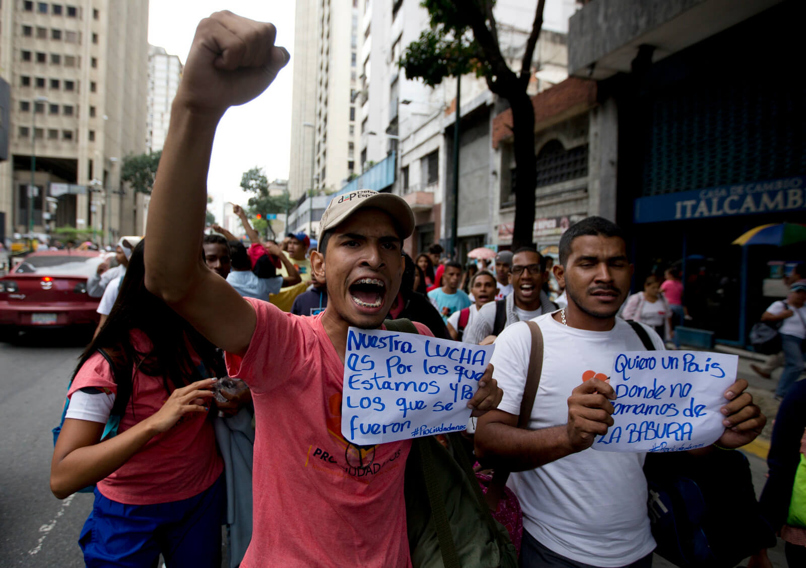 Demonstrators hold signs that reads in Spanish "Our fight is for those of us who stayed and those who left," left, and "I want a country where we don't eat from the garbage" as they shout slogans against Venezuela's President Nicolas Maduro in downtown Caracas, Venezuela, July 18, 2018 Fernando Llano | AP