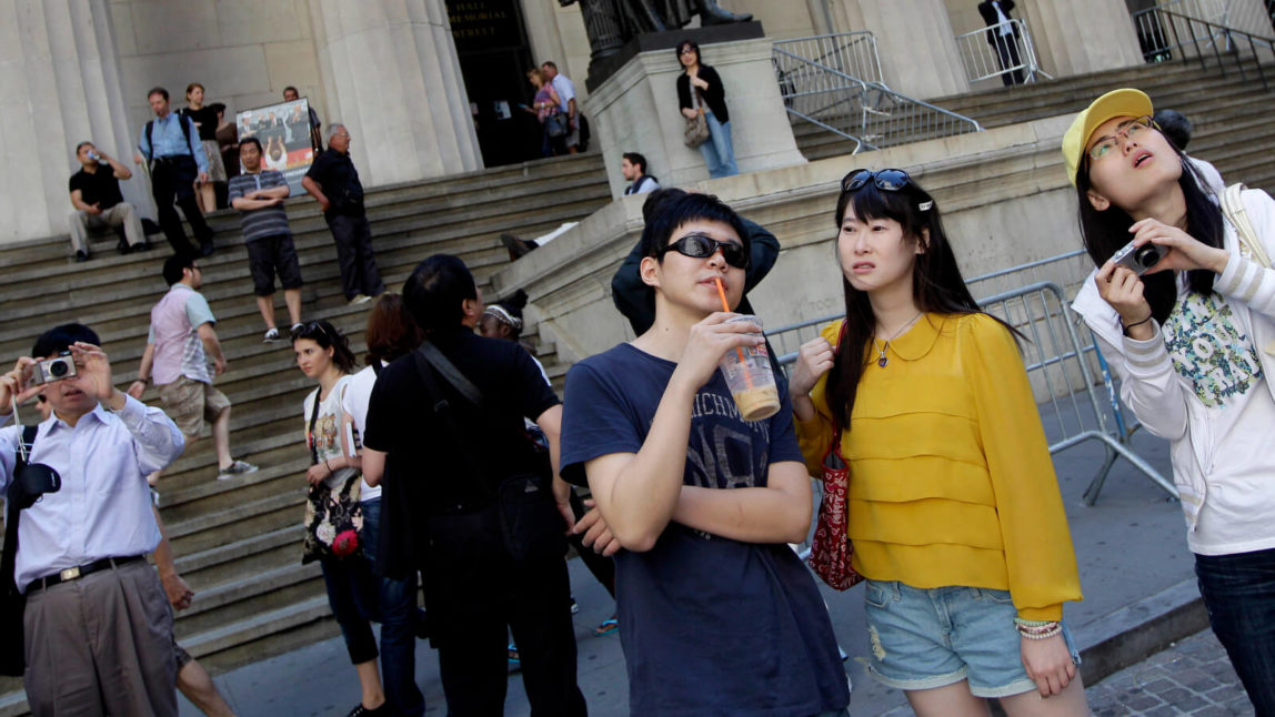 Tourists from China take in the sights of the New York Stock Exchange and Federal Hall National Memorial, in New York. Chinese tourists are among the fastest-growing and highest-spending groups of international visitors to the United States. Mary Altaffer | AP
