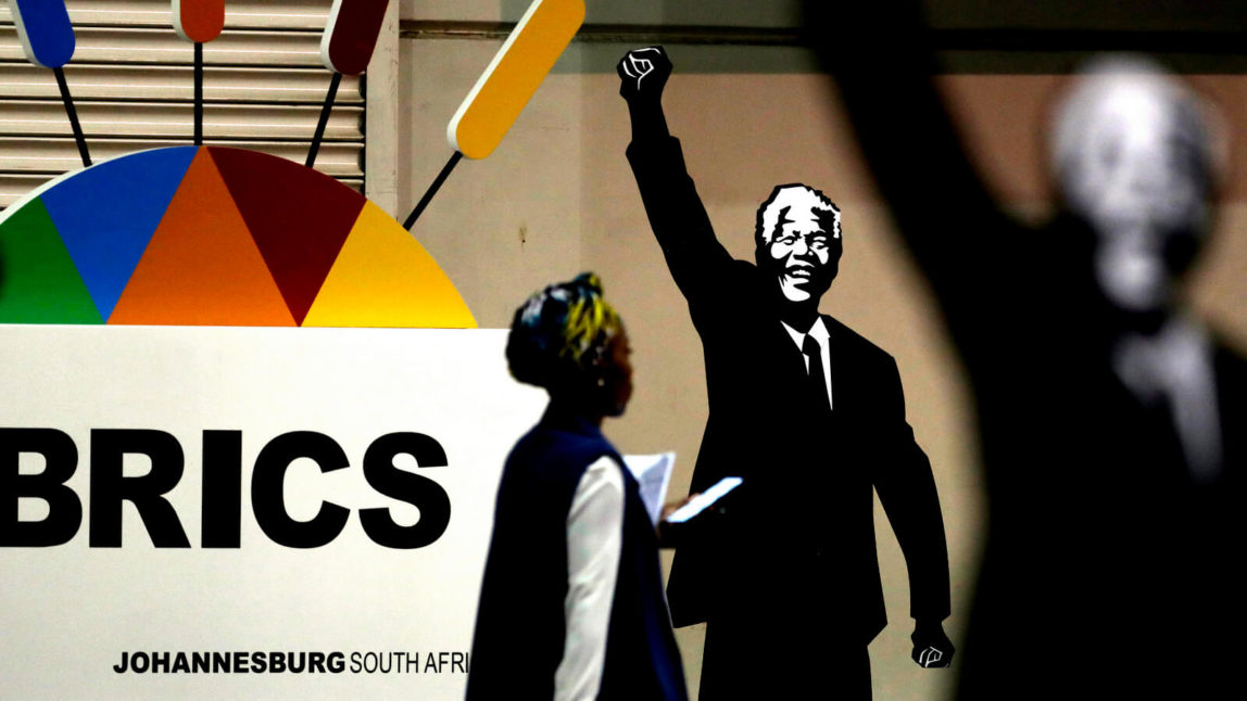 A journalist walks past a placard of Nelson Mandela during the BRICS Summit in Johannesburg, South Africa. Themba Hadebe | AP