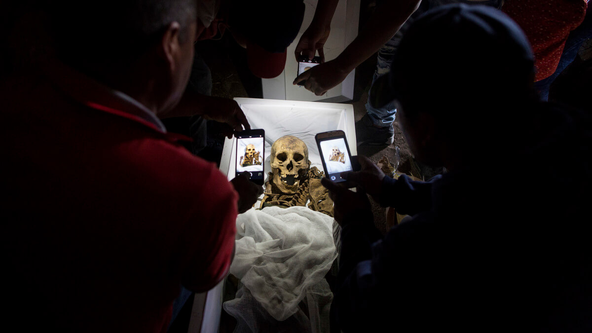 Relatives take cell phone pictures of the remains of Fortunate Ventura Huamacusi, a man who was killed by the Peruvian army in 1983, before placing the coffin in its niche at the Rosaspata cemetery in Peru's Ayacucho province. Rodrigo Abd | AP