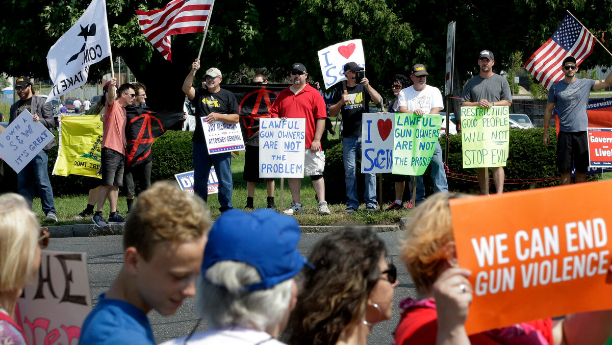 Demonstrators supporting gun law reforms, foreground, walk on the opposite side of the road from counter protesters supporting Second Amendment rights, behind, near the headquarters of gun manufacturer Smith & Wesson, Aug. 26, 2018, in Springfield, Mass. The 50-mile march supporting gun law reforms, began Aug. 23, 2018, in Worcester, Mass., and ended in Springfield, with a rally near the headquarters of the gun manufacturer. Steven Senne | AP