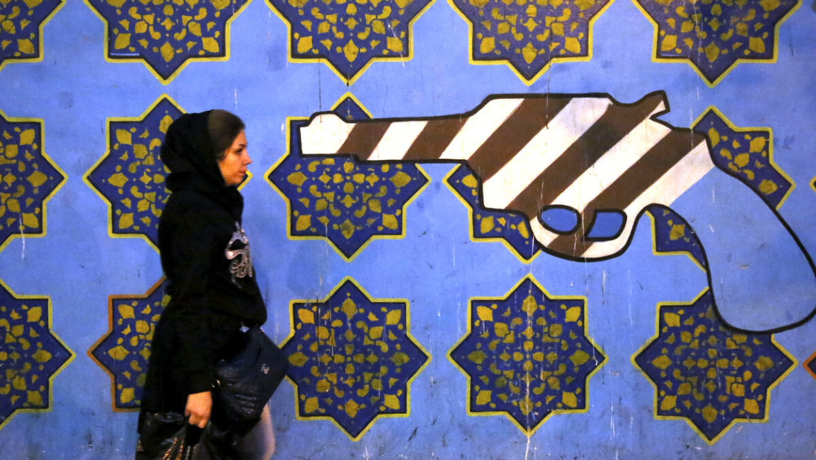 An Iranian woman walks past a mural, painted on the wall of the former U.S. Embassy, in Tehran, Iran, Nov. 2, 2013. Ebrahim Noroozi | AP