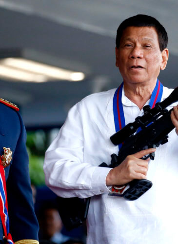 Philippine President Rodrigo Duterte, right, jokes to photographers as he holds an Israeli-made Galil rifle which was presented to him by former Philippine National Police Chief Director General Ronald "Bato" Dela Rosa at the turnover-of-command ceremony at the Camp Crame in Quezon city northeast of Manila, April 19, 2018. Bullit Marquez | AP
