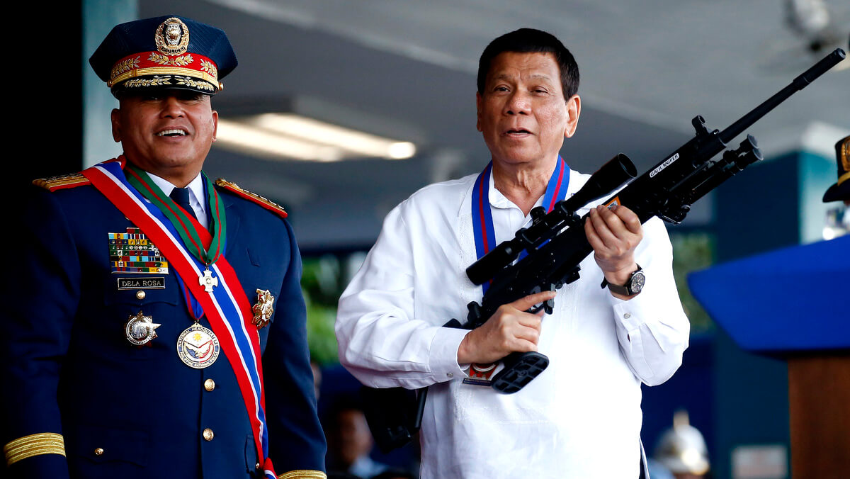 El presidente de Filipinas, Rodrigo Duterte, a la derecha, bromea con los fotógrafos mientras sostiene un rifle Galil de fabricación israelí que le fue presentado por el ex Director General de la Policía Nacional de Filipinas, Ronald "Bato" Dela Rosa, en la ceremonia de rotación de mando en el Campamento Crame. en la ciudad de Quezon, al noreste de Manila, 19 de abril de 2018. Bullit Márquez | AP