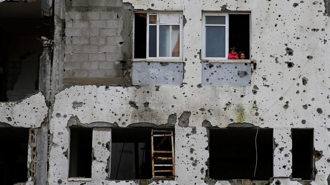 Palestinian children look out from their window in a section of a damaged apartment block, which was partially destroyed by Israel in 2014 in Beit Lahiya, Gaza Strip, Feb. 22, 2016. Hatem Moussa | AP