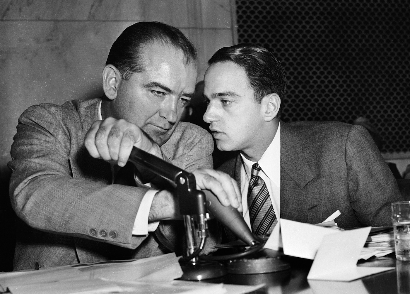 McCarthy covers the mic while having a whispered discussion with Cohn during a 1954 committee hearing. Photo | AP