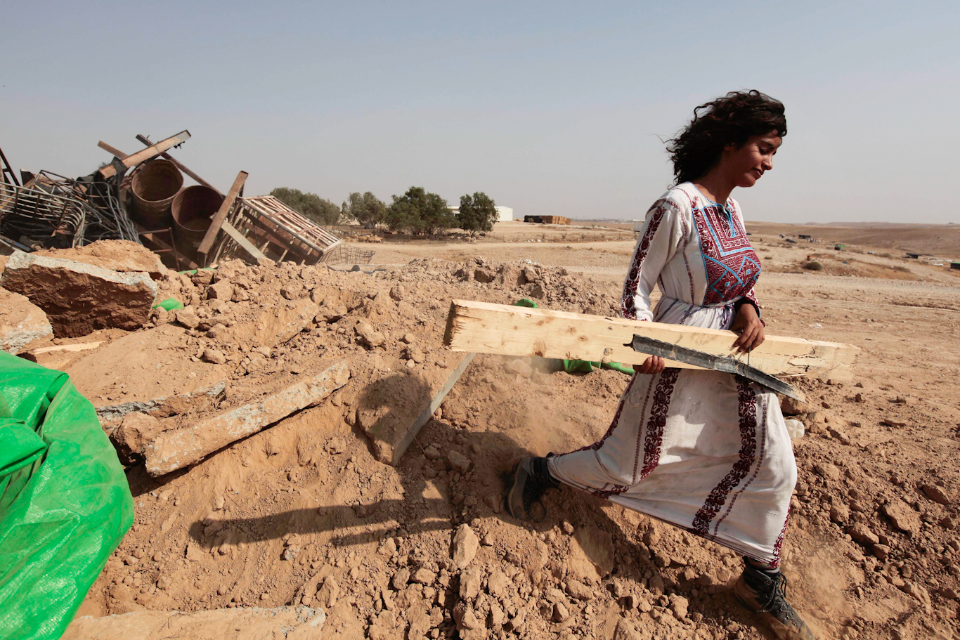 A Bedouin woman carries timber after her home was demolished by Israeli authorities in the Al-Araqib. Tsafrir Abayov | AP