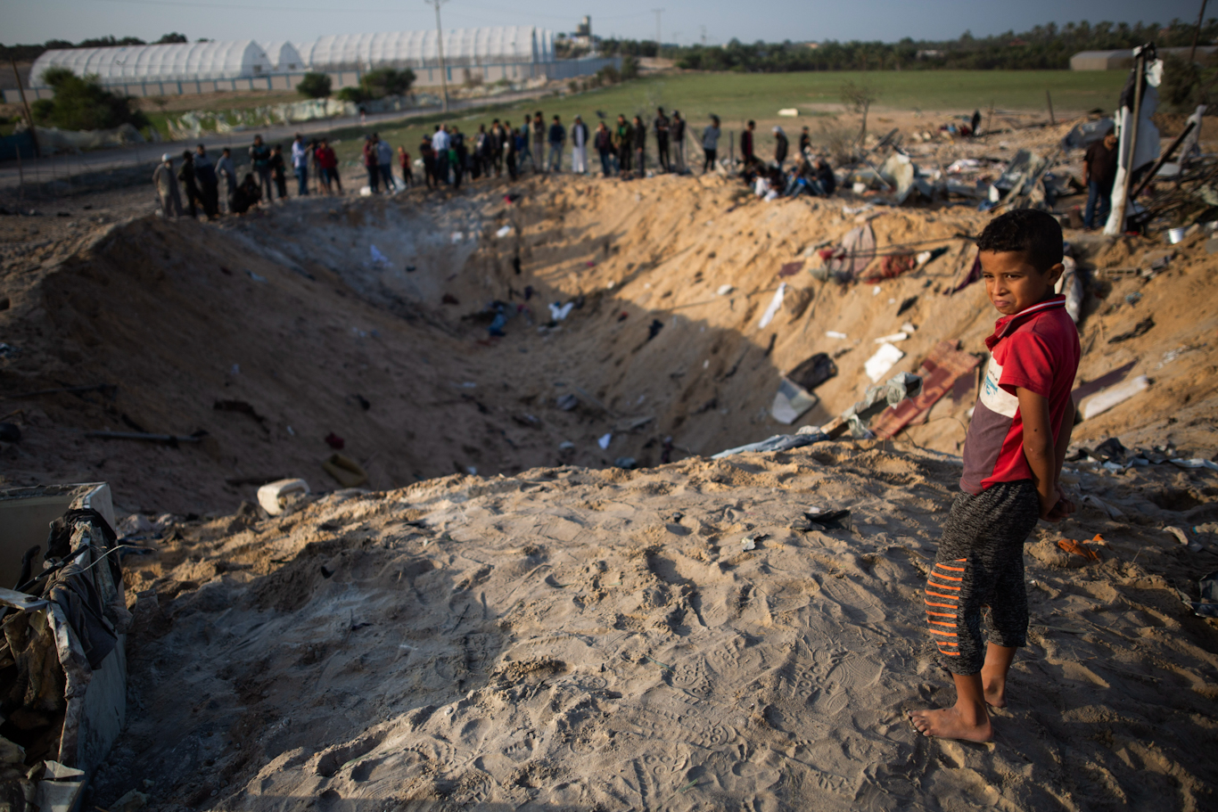 A boy looks into a crater made by Israeli missile strikes on a home that killed eight family members in Gaza, Nov. 14, 2019. Khalil Hamra | AP