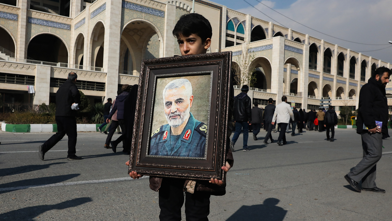A boy carries a portrait of Gen. Qassem Soleimani in Tehran, Iran, Jan. 3, 2020. Iran has vowed “harsh retaliation” for the assassination of Soleimani. Vahid Salemi | AP