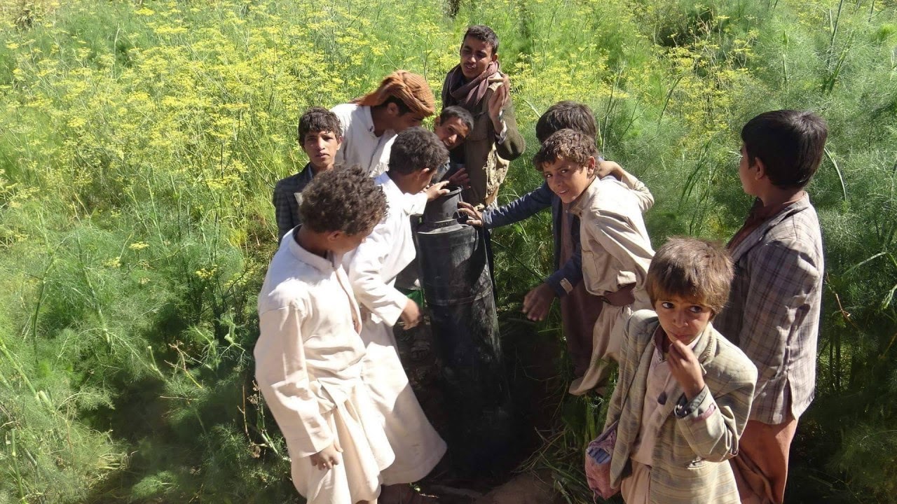 A group of children in Sahar district inspects a cluster bomb dropped by a Saudi warplane at a farm in Sadaa, March 18, 2019. Abdullah Azzi | MintPress News