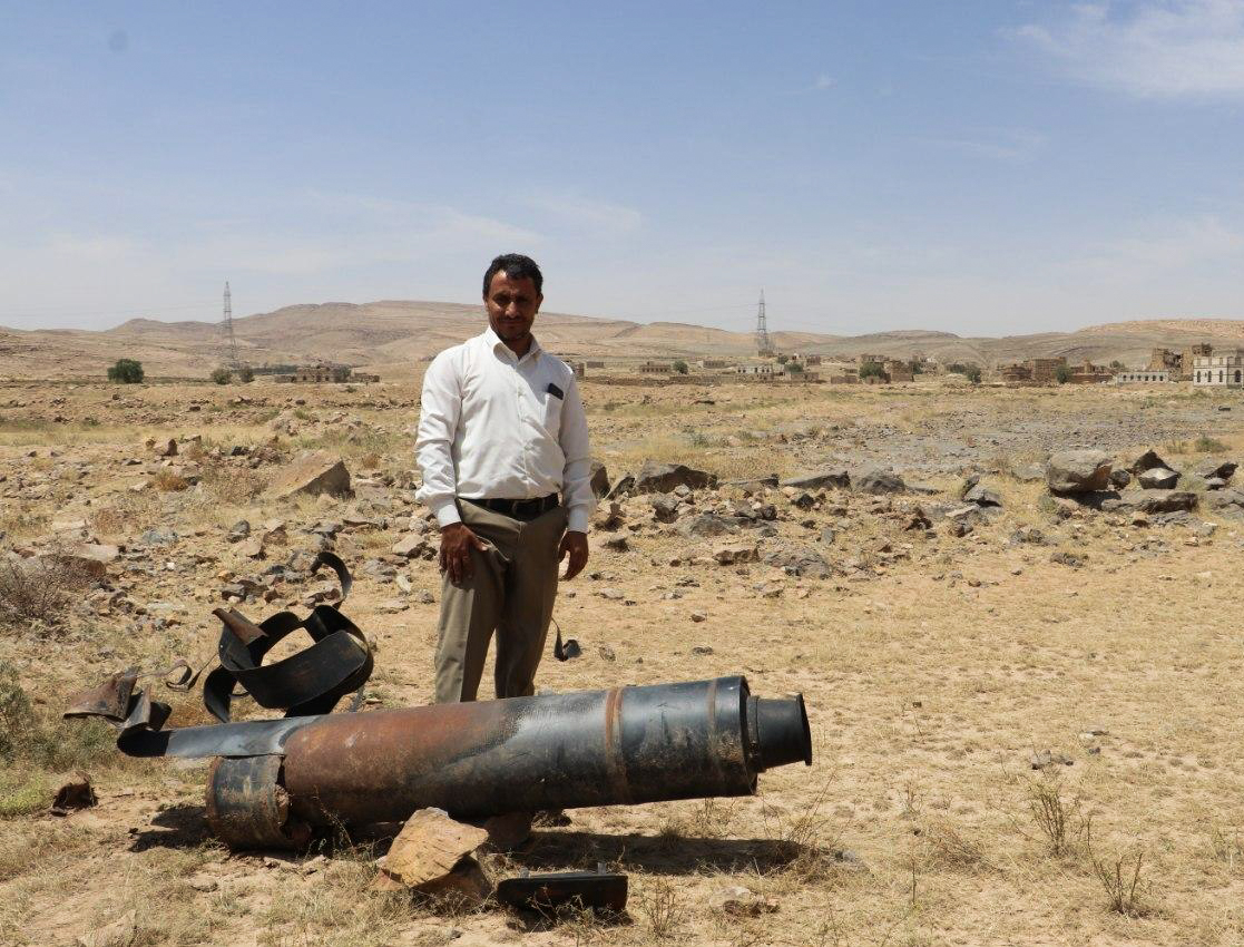 Man poses next to cluster bomb in Yemen