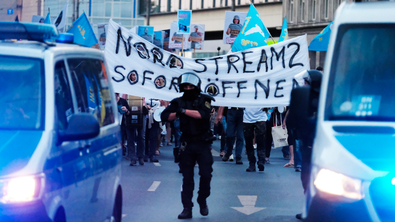 Police surrounding a protest against anti-Russia sanctions where protesters hold a banner saying "Open Nord Stream 2 Immediately," September 5, 2022. Photo: Sebastian Willnow/DPA via AP.