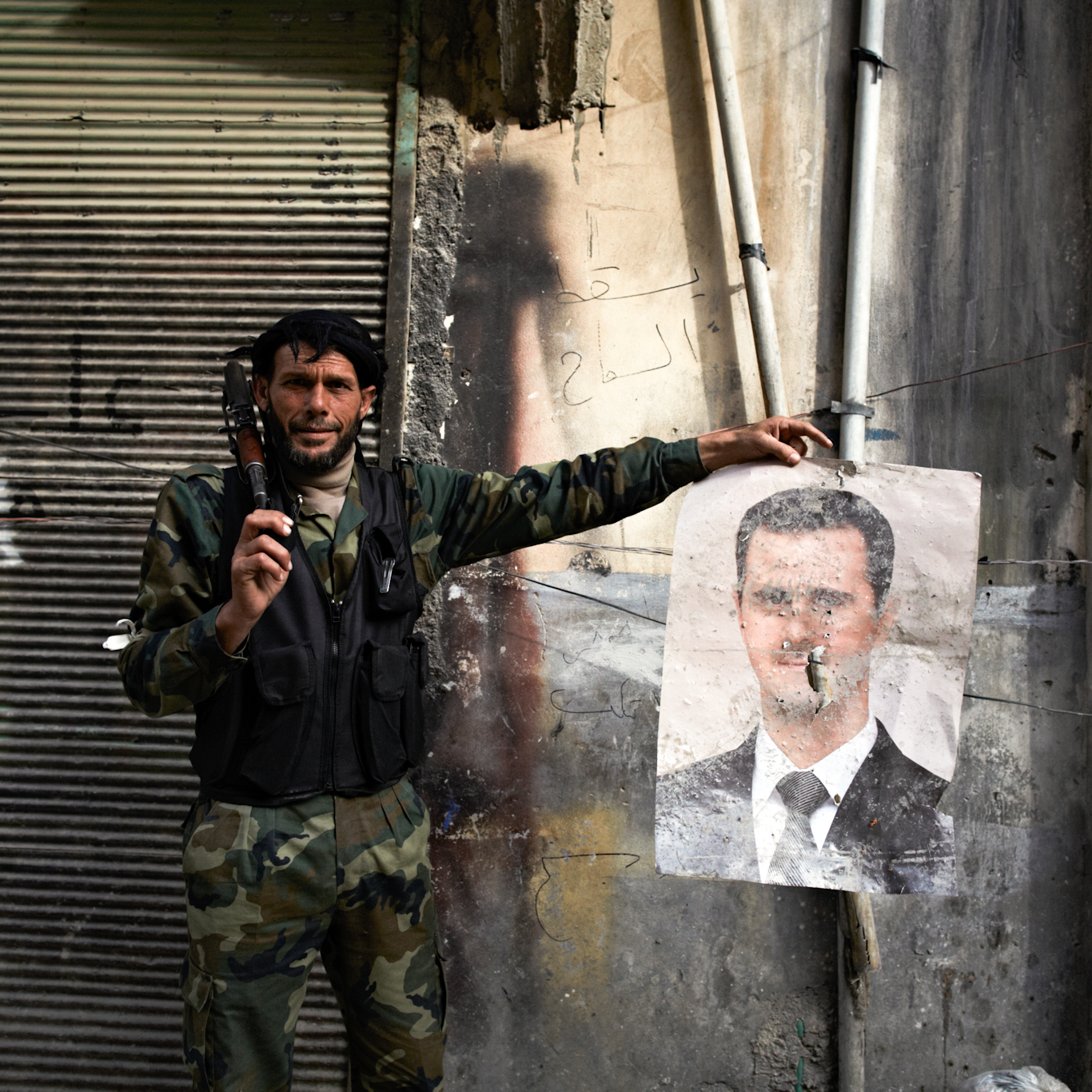 An FSA fighter holds a bullet riddled poster of President Assad in Aleppo, Syria, March 30, 2013. Photo: Sebastiano Tomada/SIPA. 