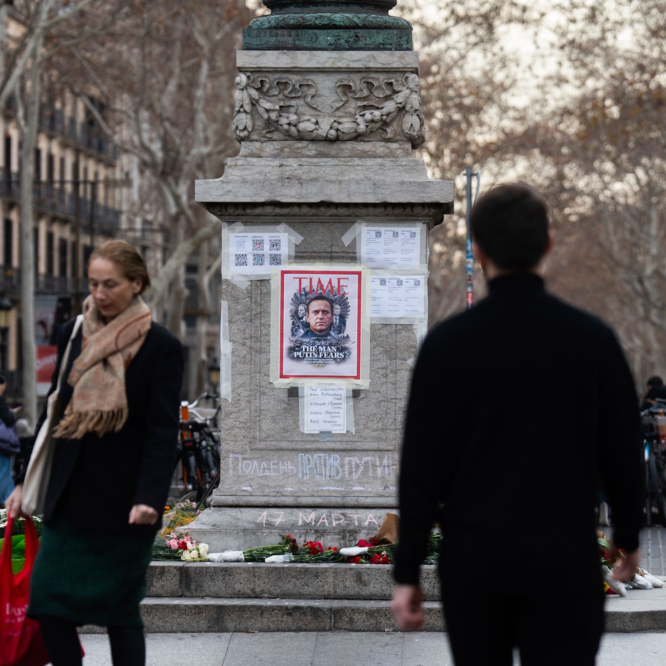 Bystanders walk by a makeshift tribute to Alexei Navalny emblazoned with a TIME Magazine cover which reads 'The Man Putin Fears,' in Barcelona, February 23, 2024. Photo: Europa Press via AP.