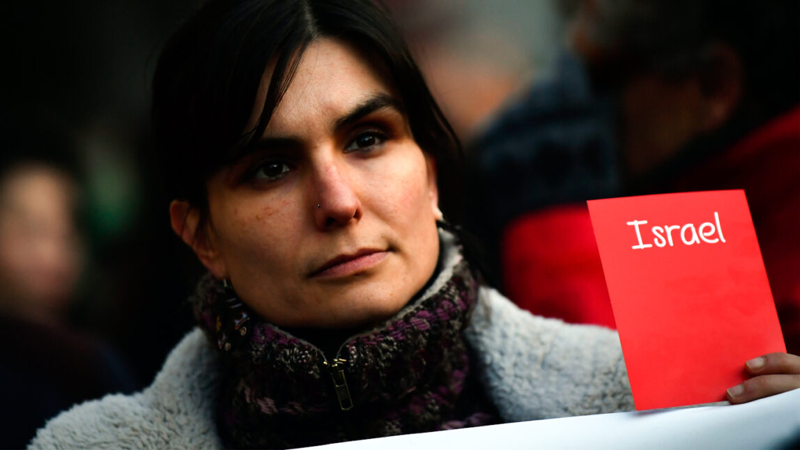 A woman holds a symbolic red card opposing Israel’s participation, during the 2018 World Cup qualifying match between Spain and Israel at El Molinon Stadium in Gijon, Spain, March 24, 2017.
