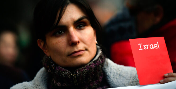 A woman holds a symbolic red card opposing Israel’s participation, during the 2018 World Cup qualifying match between Spain and Israel at El Molinon Stadium in Gijon, Spain, March 24, 2017.