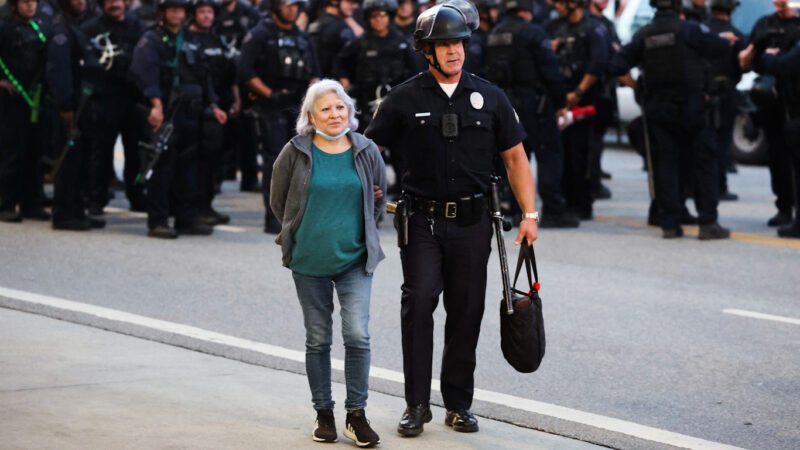 Police officer arrests protester during Los Angeles anti-ICE protest as riot police stand in formation