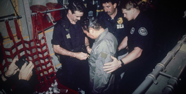 Manuel Antonio Noriega watches as U.S. Drug Enforcement Agents place chains around his waist aboard a C-130 transport plane on Jan. 4, 1990. Noriega surrendered to U.S. authorities in Panama City and was flown to Miami, Florida, where he faced drug trafficking charges. Photo | AP